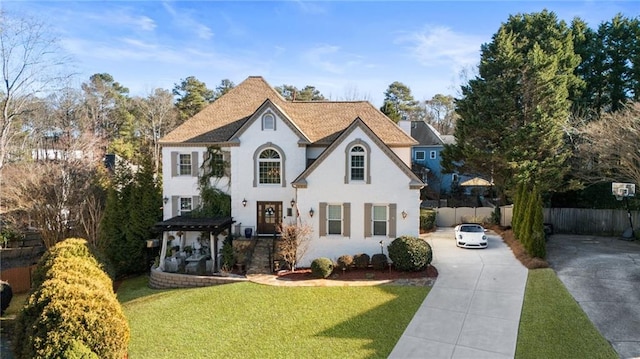 view of front of property featuring a chimney, stucco siding, concrete driveway, fence, and a front lawn