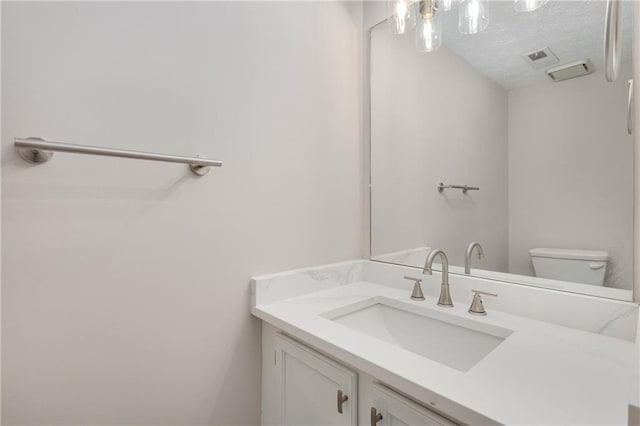 bathroom featuring vanity, a textured ceiling, and toilet