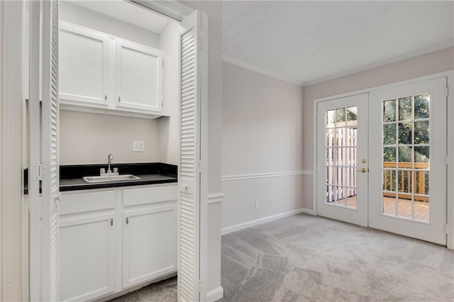 kitchen with sink, crown molding, white cabinets, light colored carpet, and french doors