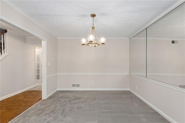 carpeted spare room featuring ornamental molding, a textured ceiling, and an inviting chandelier