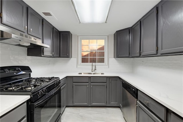 kitchen featuring tasteful backsplash, dishwasher, sink, black range with gas stovetop, and light stone countertops