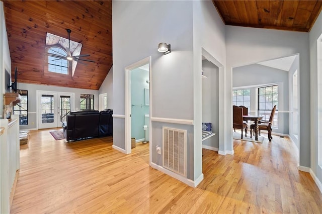 hallway featuring wood ceiling, high vaulted ceiling, a healthy amount of sunlight, and light hardwood / wood-style floors