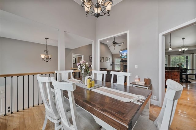 166 Woodford Way SE, Calhoun, GA 30701 - dining space with a chandelier, light wood finished floors, a warm lit fireplace, a ceiling fan, and baseboards