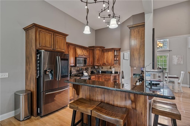 166 Woodford Way SE, Calhoun, GA 30701 - kitchen with stainless steel appliances, a high ceiling, brown cabinetry, a kitchen breakfast bar, and decorative backsplash