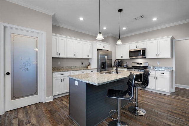 kitchen featuring pendant lighting, stainless steel appliances, an island with sink, and white cabinets