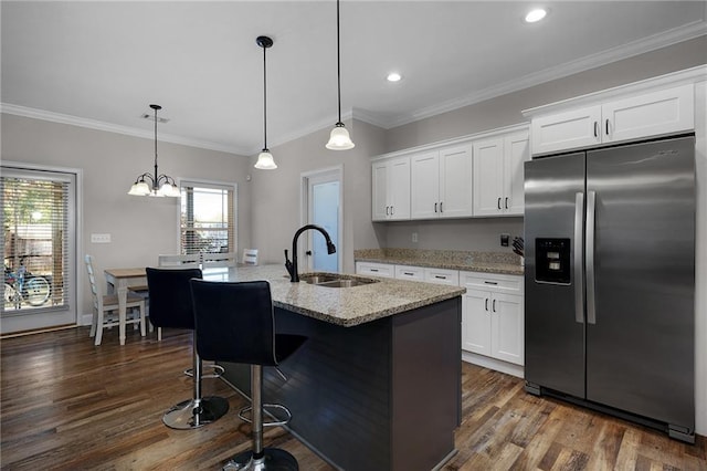 kitchen featuring sink, white cabinetry, a center island with sink, stainless steel fridge, and pendant lighting