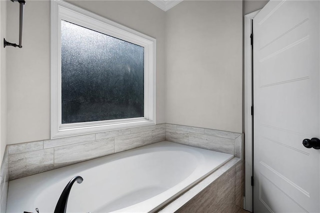 bathroom with a relaxing tiled tub and a healthy amount of sunlight