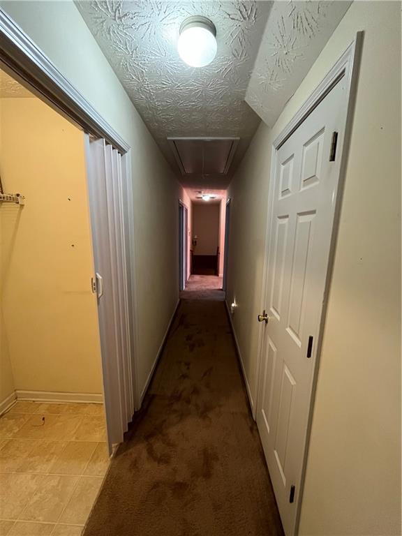 hallway featuring a textured ceiling and light carpet