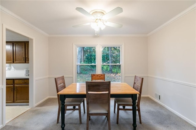 dining room with light carpet, ceiling fan, and crown molding