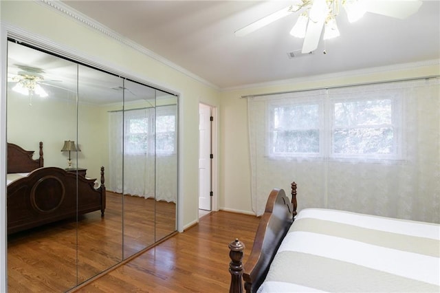 bedroom with hardwood / wood-style floors, multiple windows, a closet, ornamental molding, and ceiling fan