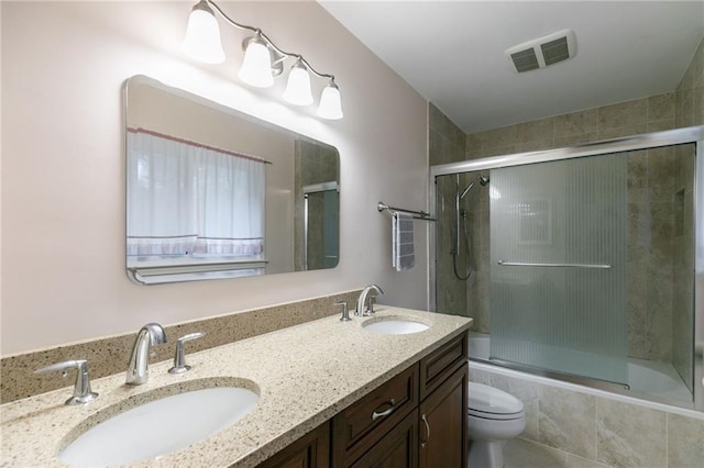 full bathroom featuring toilet, bath / shower combo with glass door, and vanity