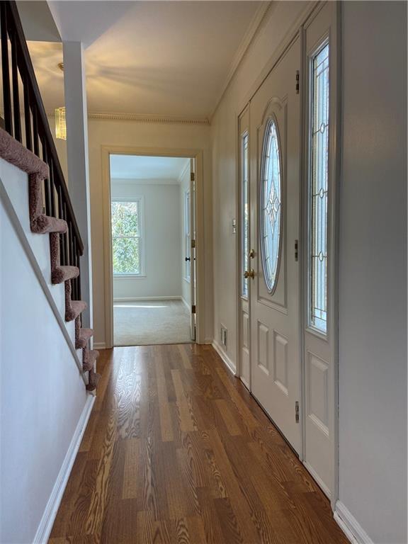 foyer entrance featuring wood-type flooring, ornamental molding, and a healthy amount of sunlight