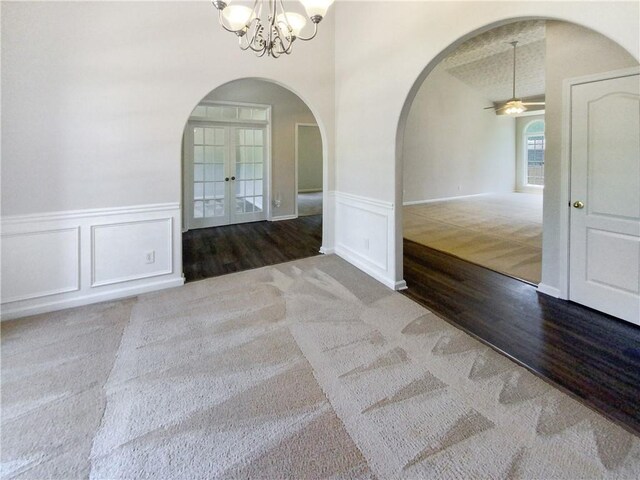 carpeted empty room featuring french doors, ceiling fan with notable chandelier, and a textured ceiling