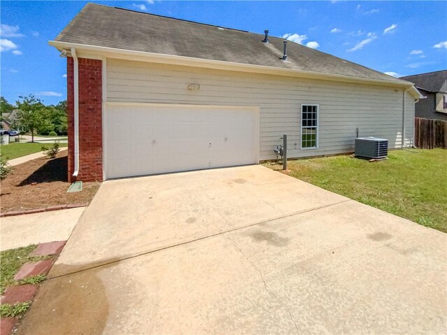 exterior space featuring a yard, a garage, and central AC unit