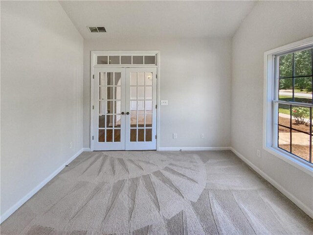 unfurnished room with french doors, light colored carpet, and vaulted ceiling