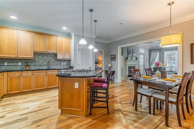 kitchen featuring tasteful backsplash, light wood-style floors, a fireplace, and a sink