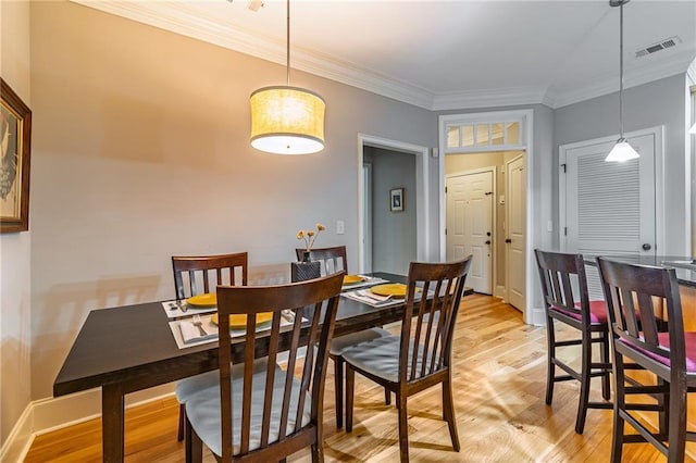 dining space with visible vents, baseboards, light wood-style flooring, and crown molding