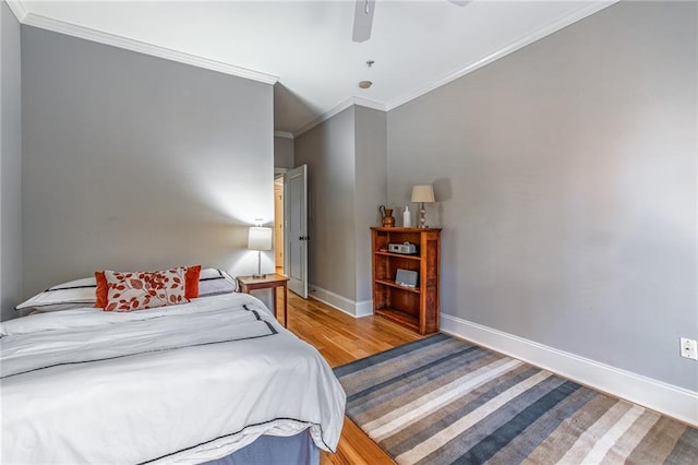 bedroom with ceiling fan, crown molding, baseboards, and wood finished floors