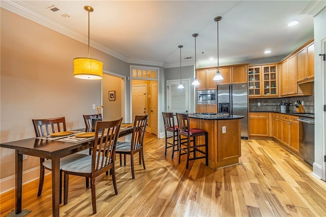 kitchen featuring a kitchen island, appliances with stainless steel finishes, backsplash, brown cabinets, and dark countertops