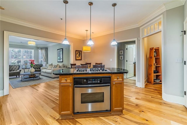 kitchen featuring ornamental molding, appliances with stainless steel finishes, light wood-style flooring, and pendant lighting