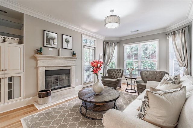 living area featuring crown molding, visible vents, a premium fireplace, wood finished floors, and baseboards