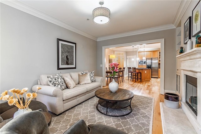 living area featuring light wood-style flooring, ornamental molding, and a fireplace with flush hearth