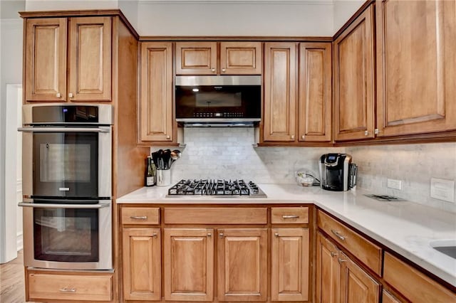 kitchen with appliances with stainless steel finishes, decorative backsplash, and light stone countertops