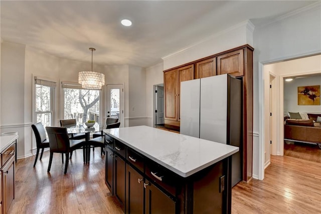 kitchen with light wood-type flooring, a kitchen island, a chandelier, and pendant lighting