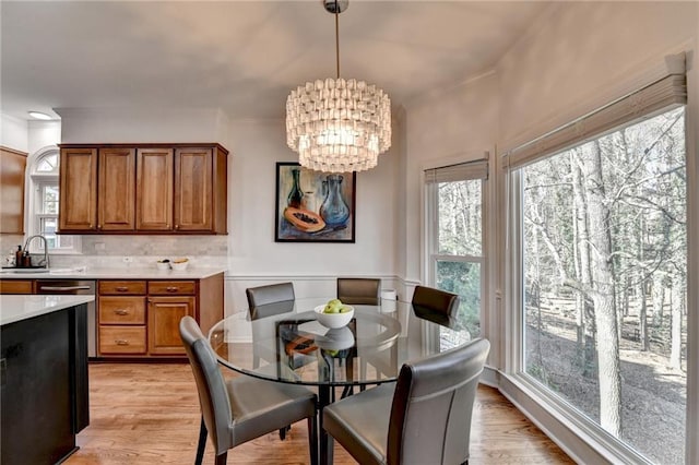 dining area with an inviting chandelier, light hardwood / wood-style floors, and sink