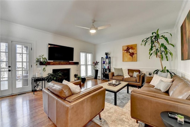 living room with ceiling fan, light wood-type flooring, french doors, and ornamental molding