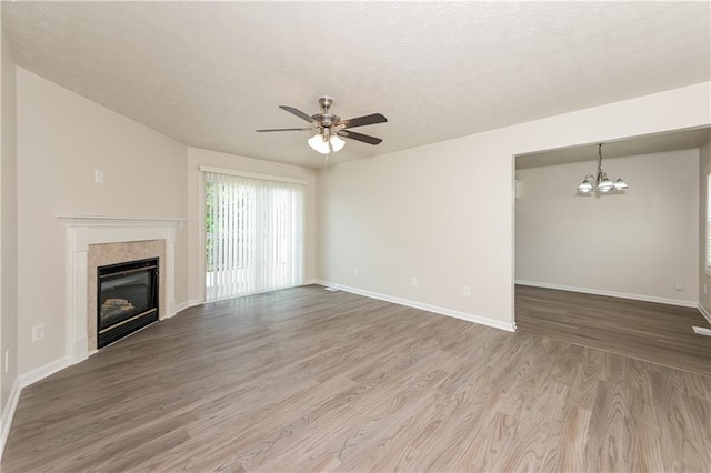 113 Garden Walk, Stockbridge, GA 30281 - unfurnished living room featuring ceiling fan, a chandelier, wood finished floors, a tile fireplace, and a textured ceiling