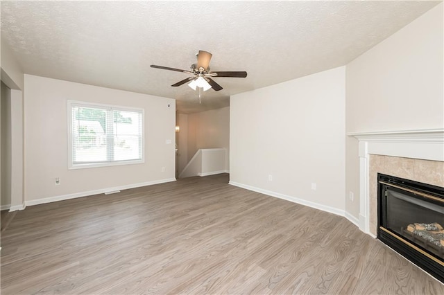 113 Garden Walk, Stockbridge, GA 30281 - unfurnished living room with wood finished floors, ceiling fan, a textured ceiling, and a tile fireplace