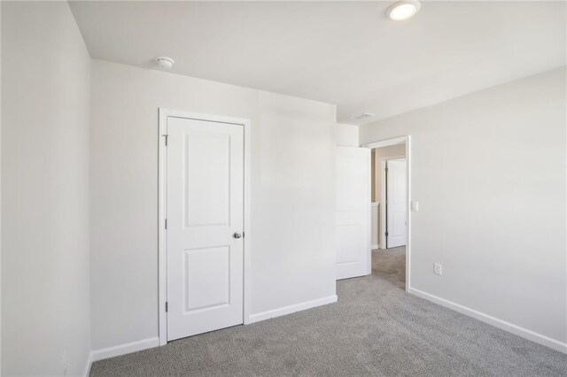 unfurnished bedroom featuring light colored carpet and a closet