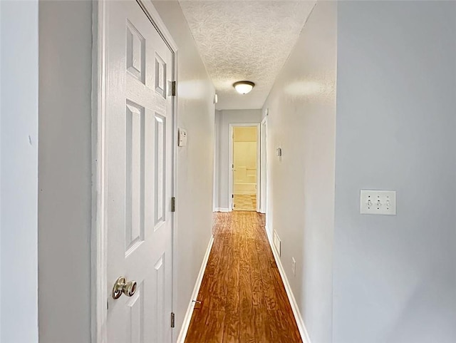 hall featuring hardwood / wood-style floors and a textured ceiling