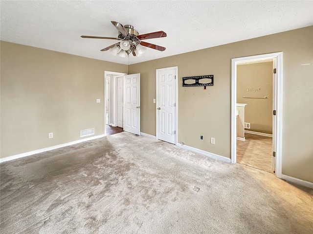 unfurnished bedroom featuring carpet, ceiling fan, ensuite bathroom, and a textured ceiling