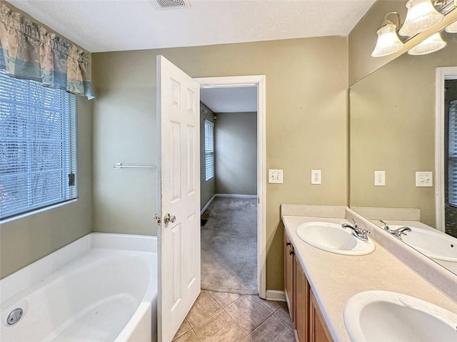 bathroom with tile patterned floors, a tub to relax in, vanity, and a textured ceiling