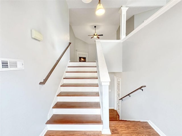 staircase with hardwood / wood-style floors, high vaulted ceiling, and ceiling fan