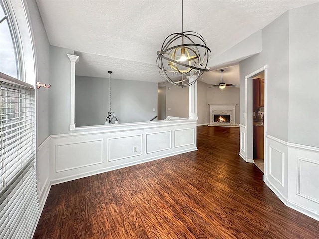 interior space featuring a textured ceiling, ceiling fan with notable chandelier, vaulted ceiling, and dark wood-type flooring