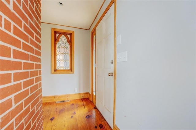 interior space featuring brick wall, light wood-type flooring, and ornamental molding