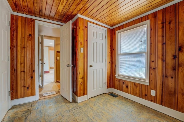 doorway to outside featuring wood walls, crown molding, and wood ceiling