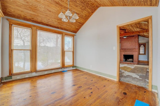 interior space featuring vaulted ceiling, light hardwood / wood-style flooring, wood ceiling, a brick fireplace, and an inviting chandelier