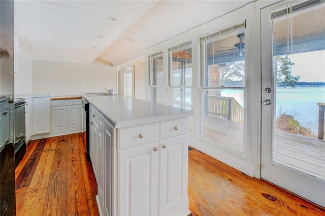 kitchen featuring a kitchen island, white cabinets, light wood-type flooring, and sink