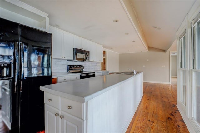 kitchen featuring sink, white cabinets, tasteful backsplash, a kitchen island, and black appliances