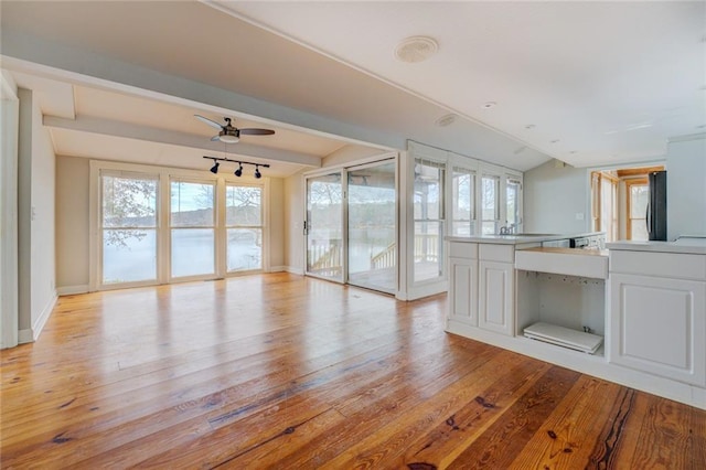 interior space with lofted ceiling, ceiling fan, a wealth of natural light, and light hardwood / wood-style flooring