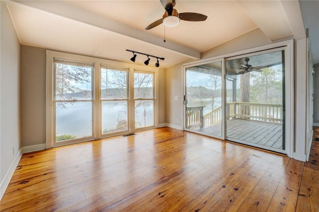 unfurnished sunroom featuring track lighting, ceiling fan, lofted ceiling with beams, and a water view