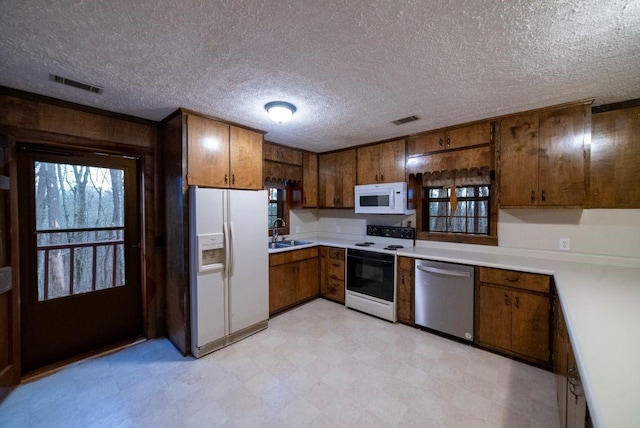 kitchen with white appliances, sink, and a textured ceiling