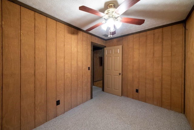 carpeted empty room featuring a textured ceiling and wood walls