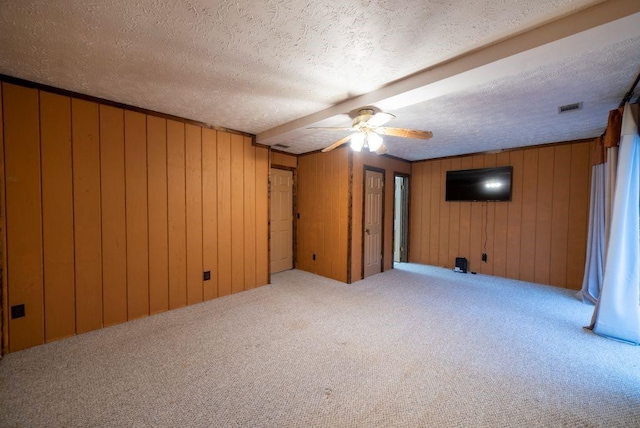 basement with carpet, wooden walls, a textured ceiling, and ceiling fan