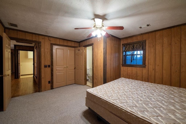 unfurnished bedroom featuring crown molding, wooden walls, carpet floors, and a textured ceiling