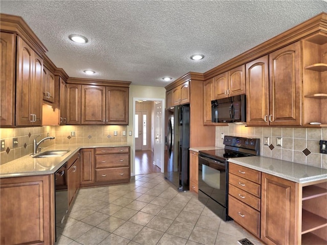 kitchen featuring open shelves, brown cabinets, black appliances, and a sink